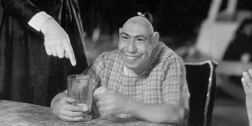 Schlitztie sitting a table with a glass in 'Freaks'