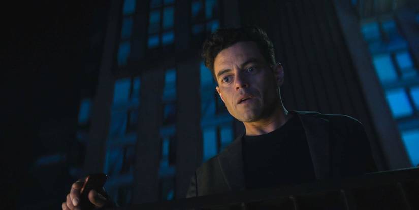 Rami Malek looking over the ledge of a building in The Amateur.