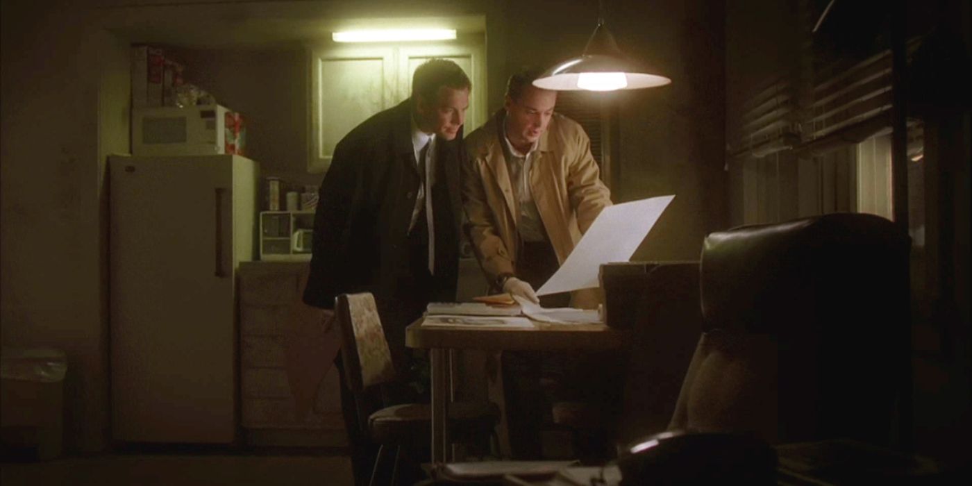 Tony Dinozzo and Timothy Mcgee look at papers on a kitchen table in a dingey apartment in NCIS