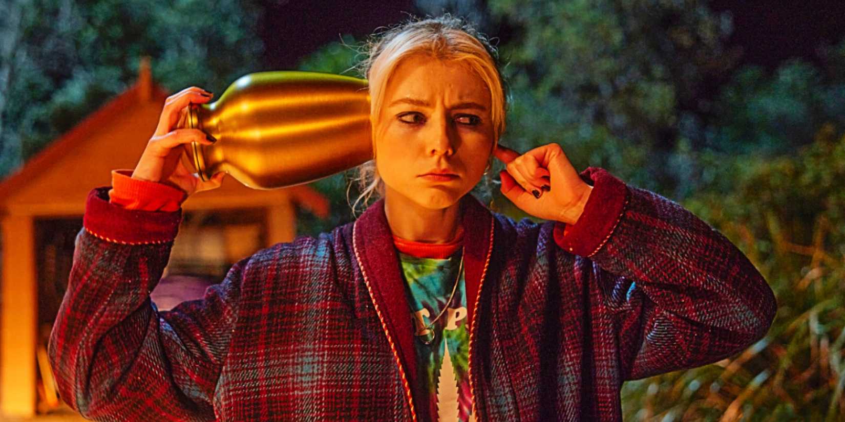 Vivian Cunningham (Thomasin Mackenzie) holding an urn up to her head in Totally Completely Fine