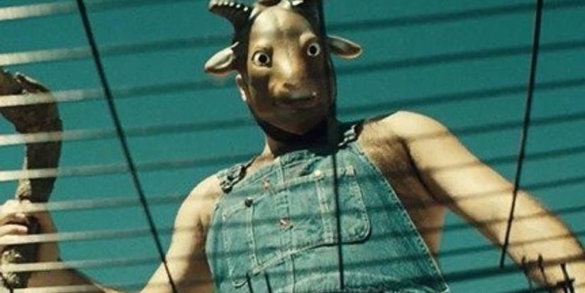 Image from The Farm: a man in a goat mask standing over a cage
