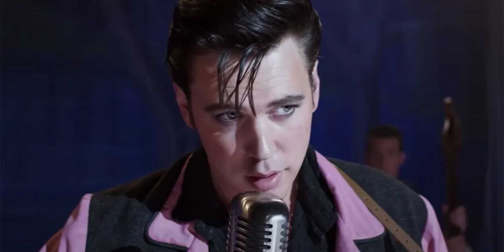 Austin Butler as Elvis Presley standing in front of a microphone in Elvis (2022).