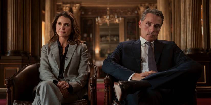 Kate (Keri Russell) and Hal Wyler (Rufus Sewell) sitting in chairs looking tense in The Diplomat Season 3.