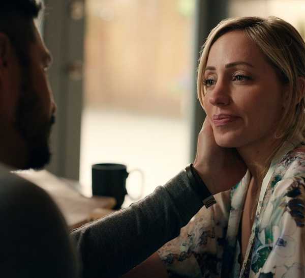 Mike puts his hand on Brie's face lovingly as she looks at him and they sit together in Virgin River.