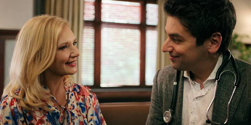 Muriel and Cameron holding hands while sitting on a couch and lovingly smiling at each other in 'Virgin River' season 5