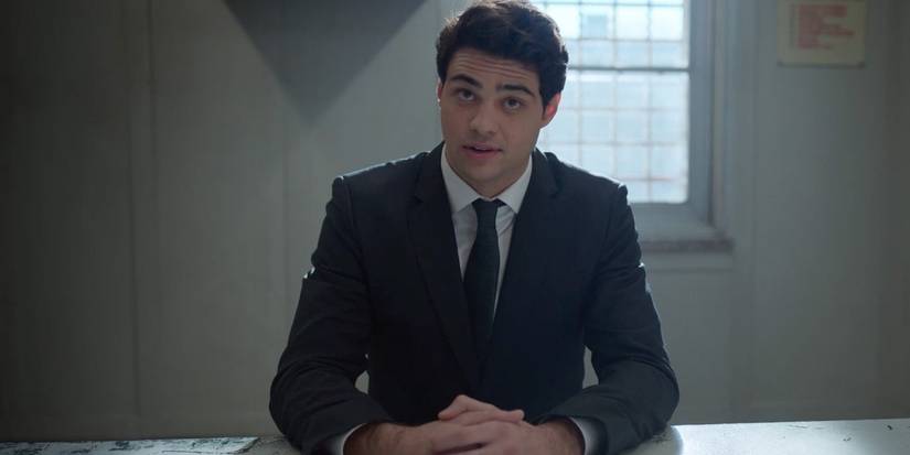 Noah Centineo sits at a metal table as Owen Hendricks in 'The Recruit'.