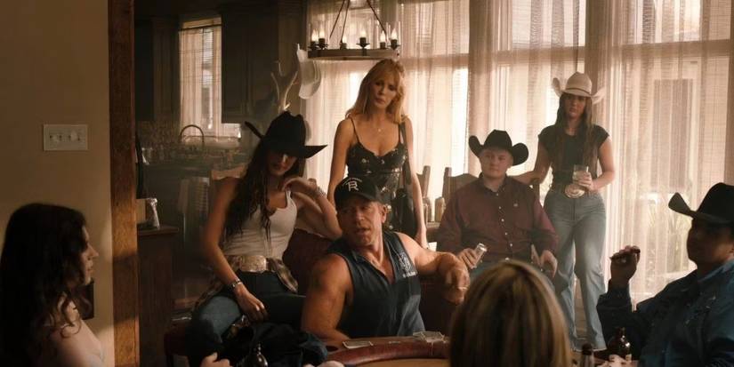 Taylor Sheridan in Yellowstone next to Bella Hadid and Kelly Reilly, surrounded by a bunch of people.