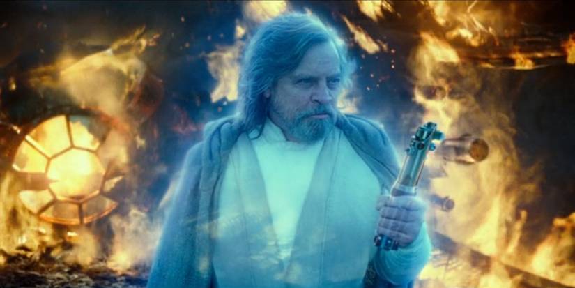 The ghost of Luke Skywalker (Mark Hamill) holds his old lightsaber in Star Wars: The Rise of Skywalker.