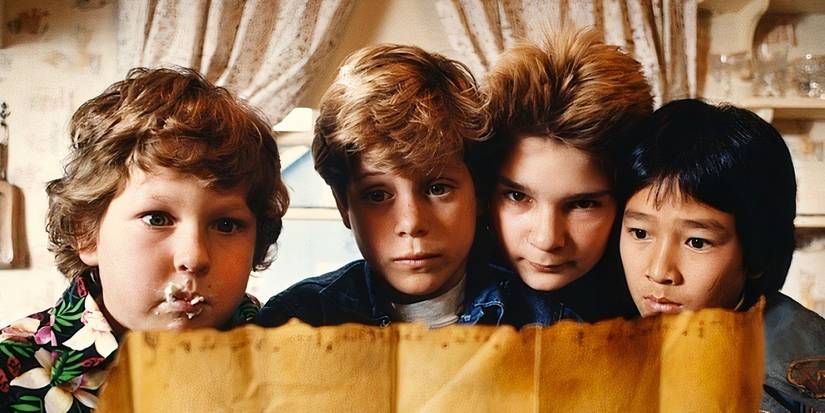 Jeff Cohen, Sean Astin, Corey Feldman, and Ke Huy Quan look at a map in The Goonies