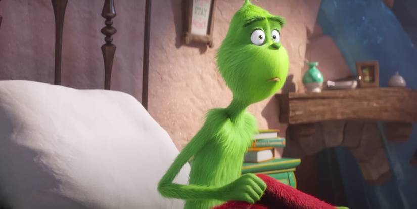 Benedict Cumberbatch voices the Grinch, who sits up in bed looking surprised in The Grinch, 2018.