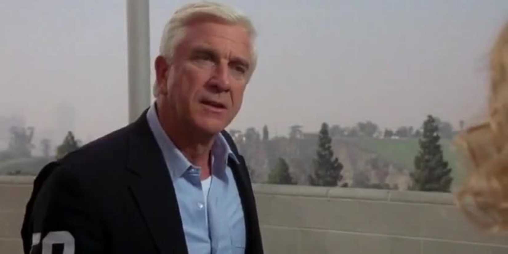 Leslie Nielsen standing outside having a conversation in 'The Naked Gun'