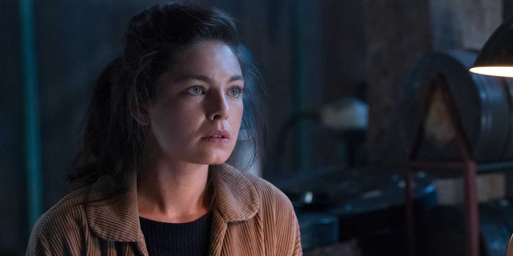 A woman sits in a darkened room and looks worried in The Man in the High Castle.
