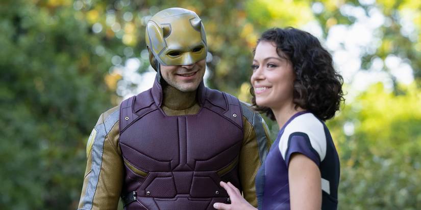 Daredevil (Charlie Cox) mengenakan setelan kuningnya sementara Jennifer Walters (Tatiana Maslany) tersenyum menjauh darinya di She-Hulk: Pengacara di Law