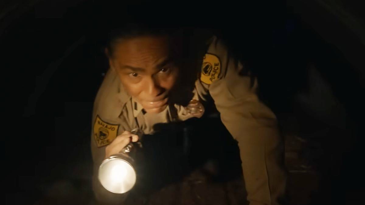 Joe Leaphorn (Zahn McClarnon) with a flashlight crawls underground on 'Dark Winds.'