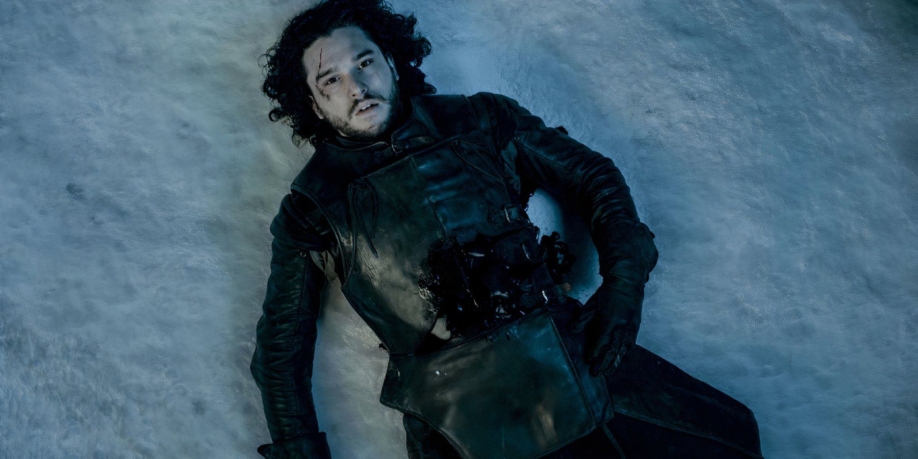 A wounded Jon Snow lies on the snow-covered ground, dying in Game of Thrones.