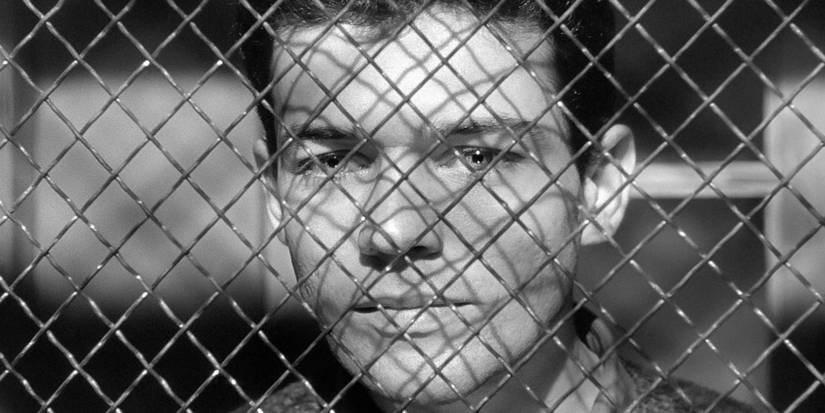 Marc Michel staring through a fence in Le Trou