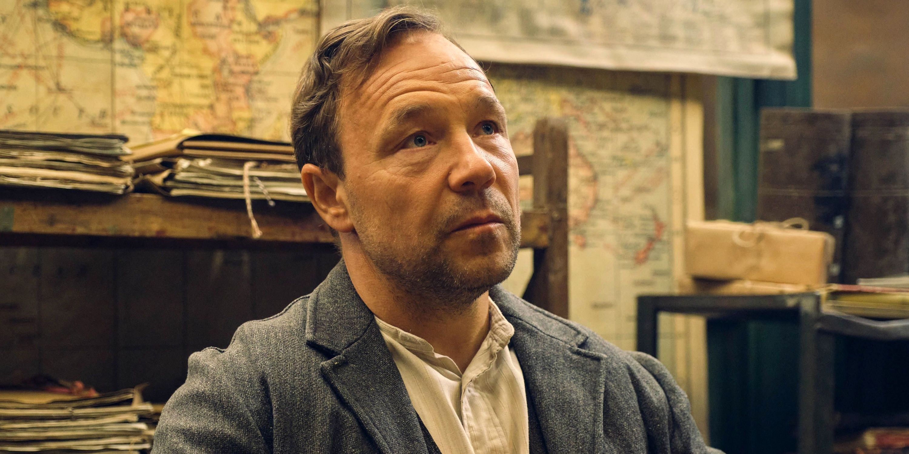 Stephen Graham as Hayden Stagg sitting at a table in a shirt and jacket in Peaky Blinders
