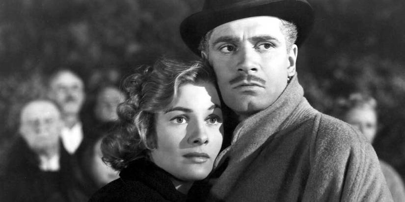 Joan Fontaine and Laurence Olivier embracing looking to the distance in Rebecca