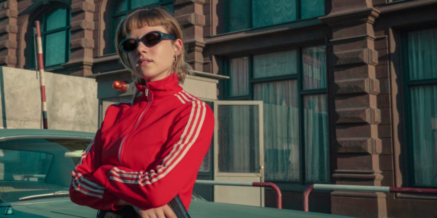 Jella Haase as Kleo wearing a red track suit and sunglasses and holding a gun in &lsquo;Kleo&rsquo;