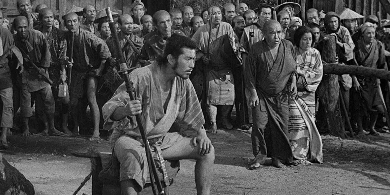 A man sitting down with a crowd behind him in Seven Samurai