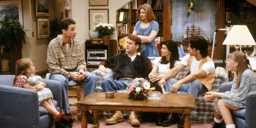 The main cast of Full House sitting around the living room.