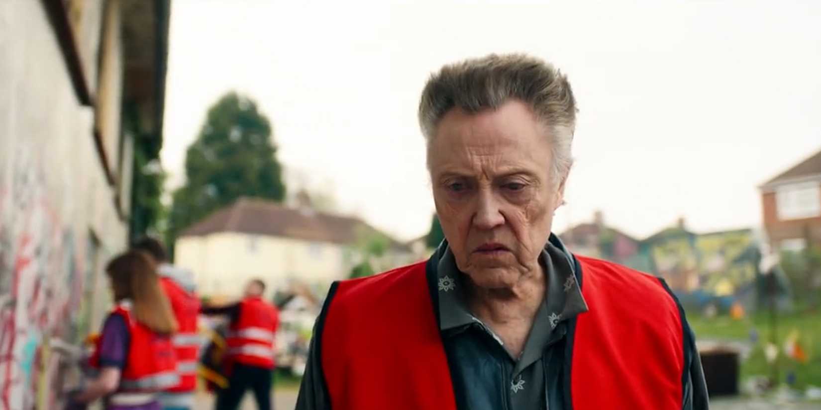 Christopher Walken in a reflective vest looking toward a graffiti-covered wall in 'The Outlaws'.