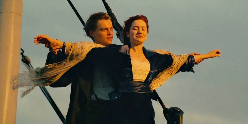 Kate Winslet as Rose, standing on the bow of the ship with her arms spread, with Leonardo DiCaprio as Jack holding her from behind in Titanic (1997).
