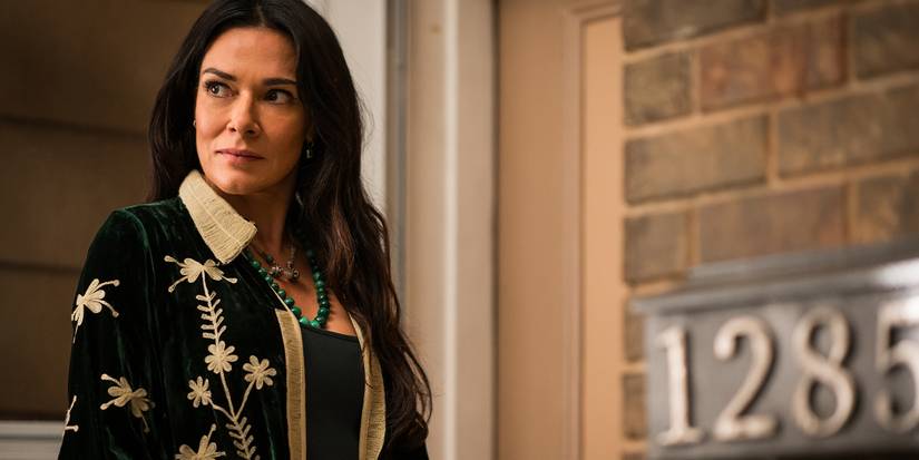 Lottie dewasa tersenyum dan melihat ke samping di depan sebuah gedung di Yellowjackets Musim 3