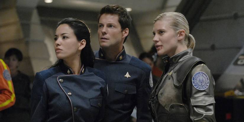 Some of the cast stand together and look in the same direction with tense energy in Battlestar Galactica.