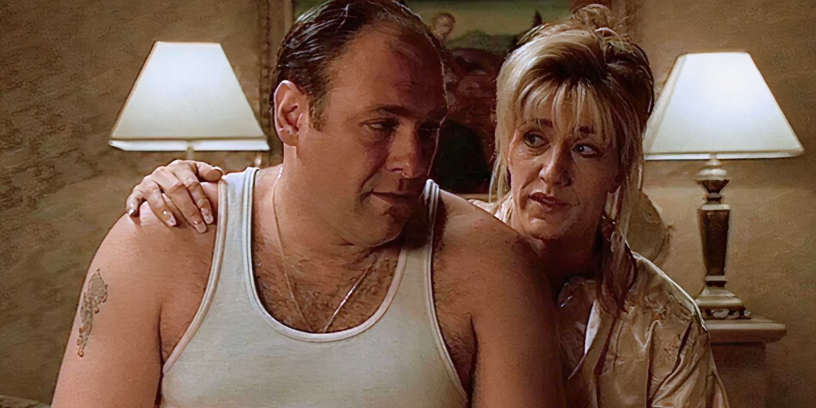 Edie Falco sitting on the bed with her arm around James Gandolfini's shoulder in The Sopranos S1, E13.
