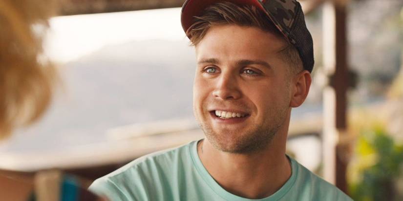 Leo Woodall as Jack in The White Lotus, smiling at someone in front of him, off-screen.