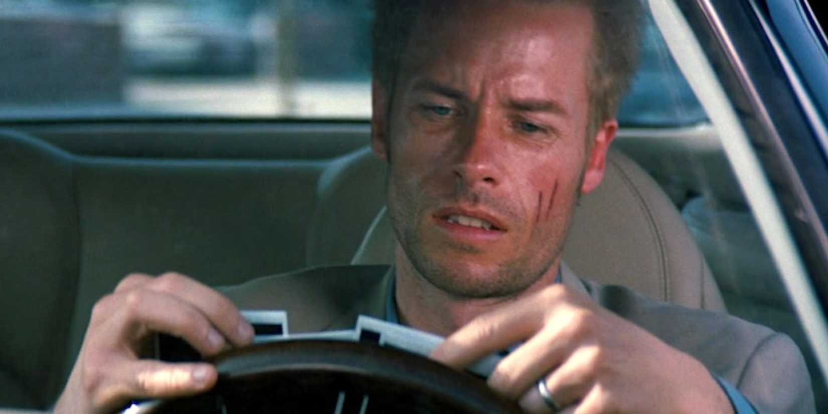 Guy Pearce looks at some polaroid photographs while sitting inside a car in Memento.