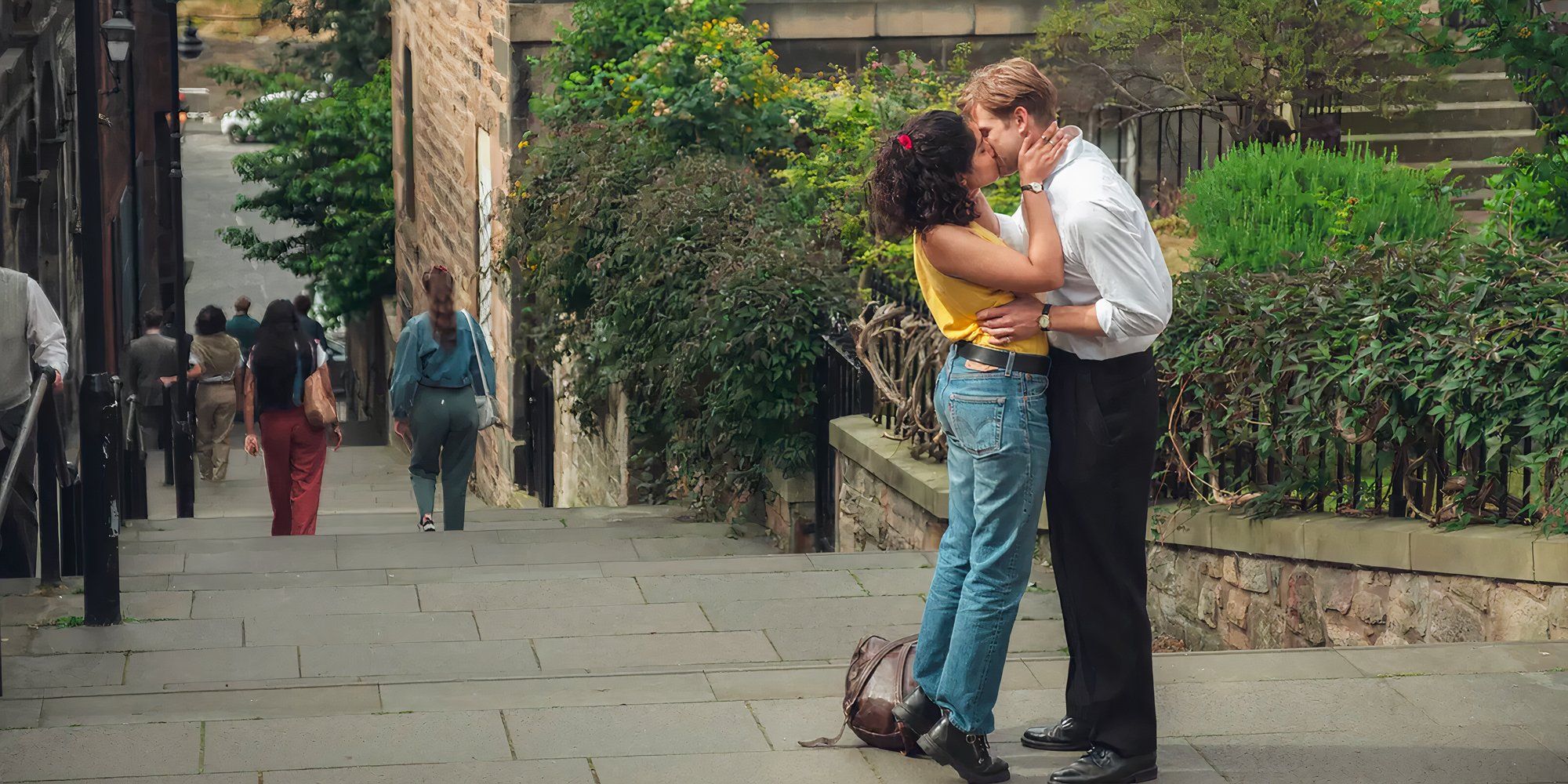 Emma and Dexter kissing on stairs passionately in the show One Day.