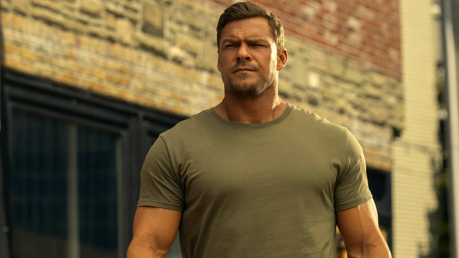 Alan Ritchson as Jack Reacher walking down the street outside in Season 3 of Reacher.