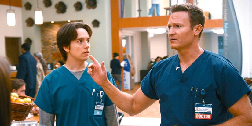 A doctor in scrubs gestures while another staff member looks on in St. Denis Medical.