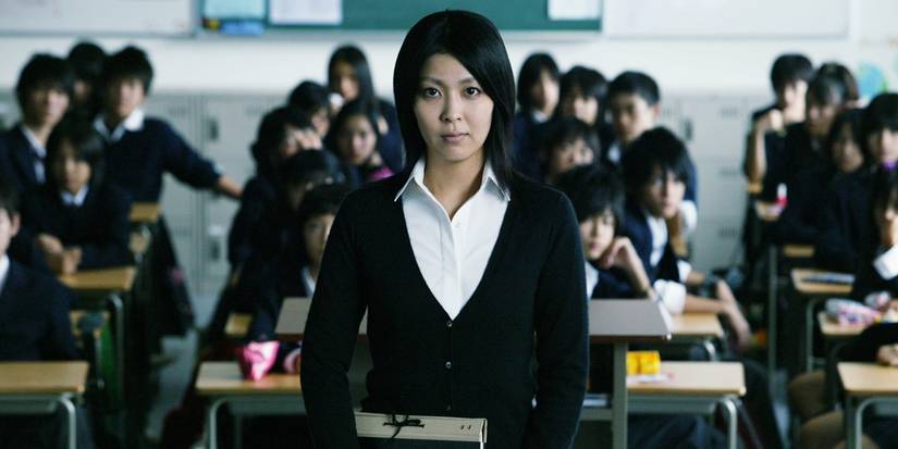 Takako Matsu as Yuko Moriguchi standing in the middle of a classroom in Confessions (2010)