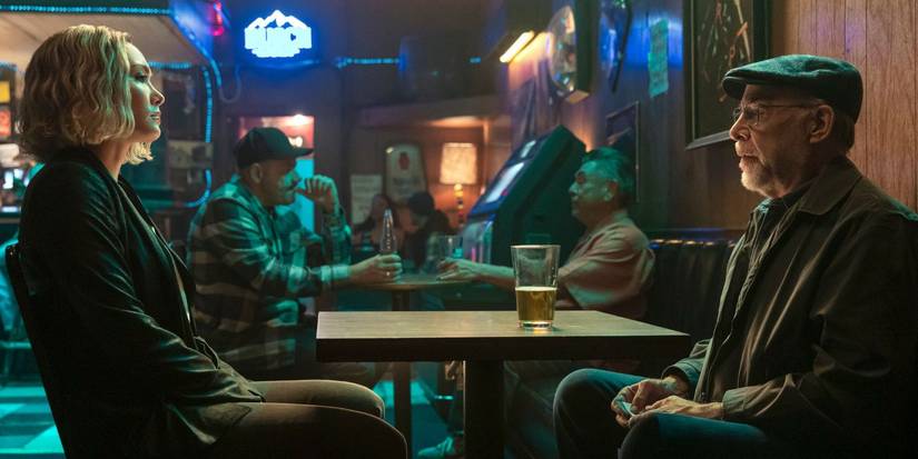 Daniella Pineda and J.K. Simmons talk across a table in a bar in The Accountant 2.
