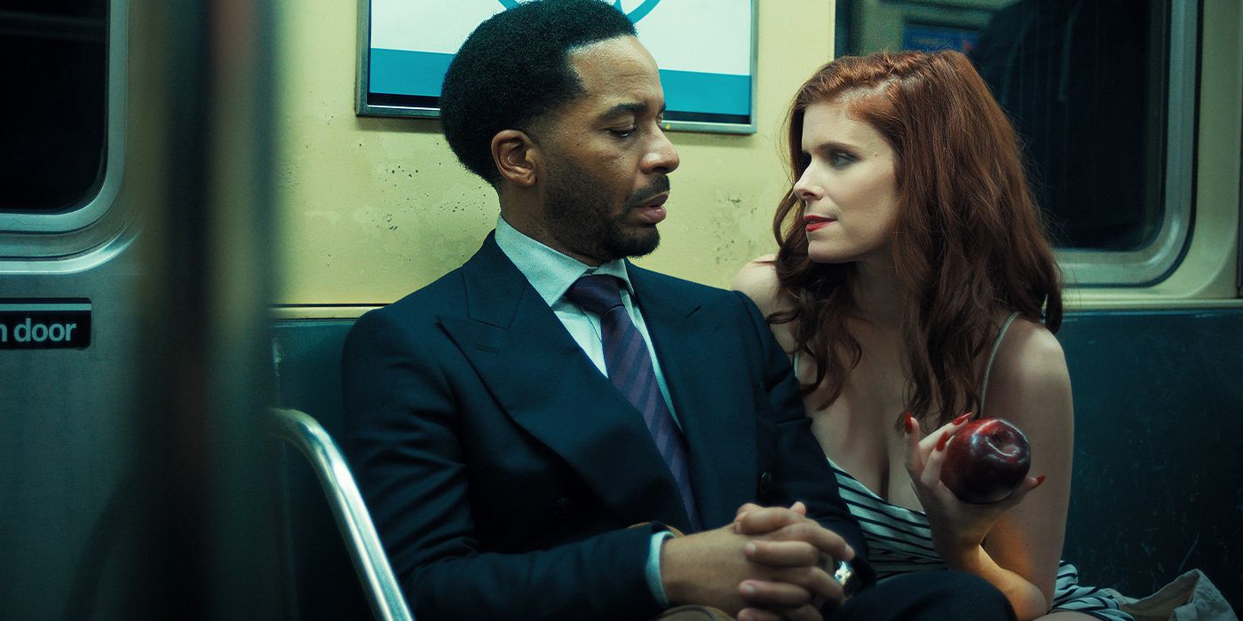 Kate Mara holding an apple and looking at Andre Holland on a subway in The Dutchman