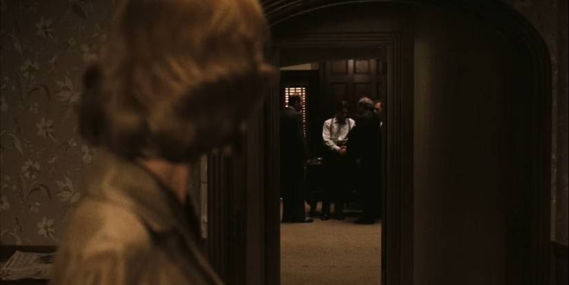 Kay looks back at a room full of men in The Godfather.