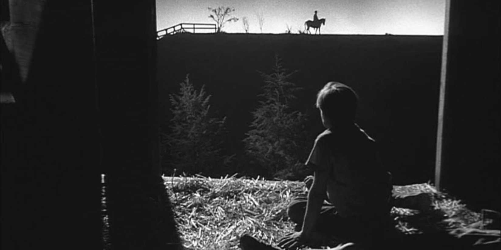 A young boy looking at a man on horseback in the distance in The Night of the Hunter