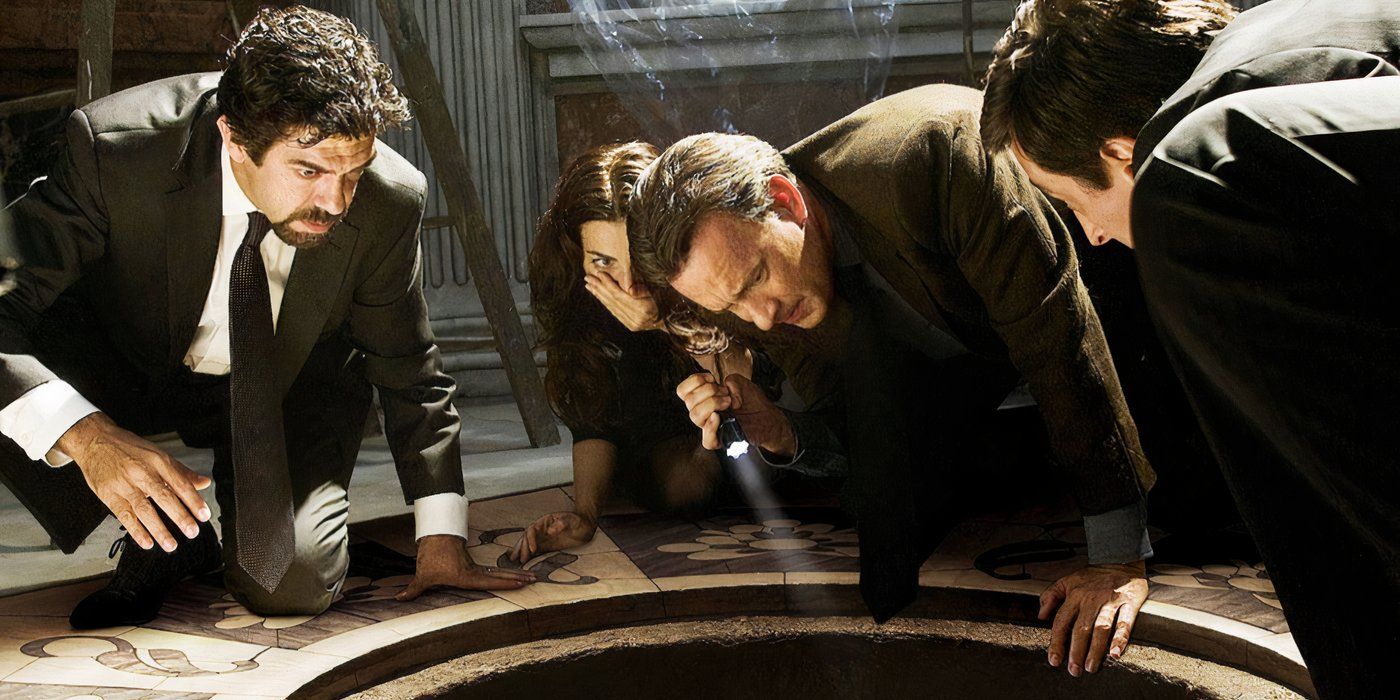 The cast crouch down on the floor looking at something below in a hole in Angels & Demons.