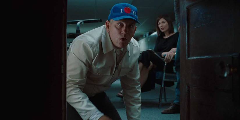 John Malkovich crouches down and peers into a portal to his own mind in Being John Malkovich, 1999.