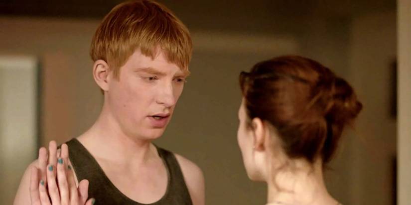 Seorang pria dengan tank top mengangkat telapak tangannya ke arah wanita di Black Mirror "Segera Kembali" episode.