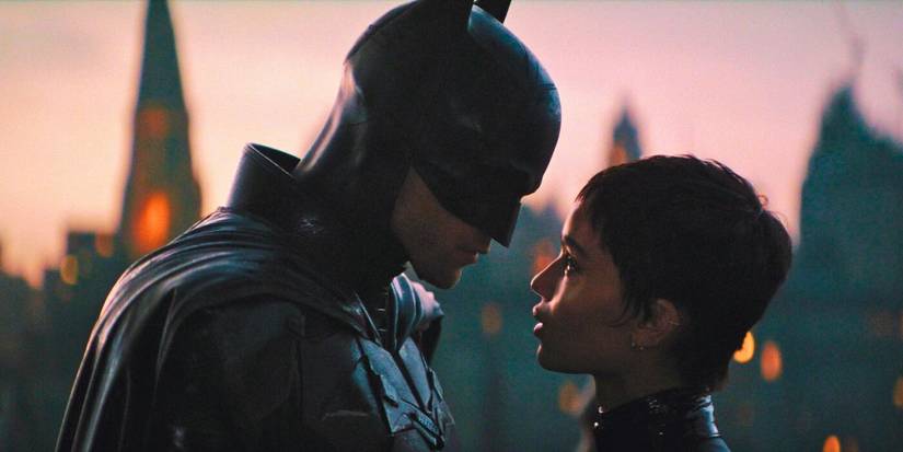 Robert Pattinson as Batman and Zoë Kravitz as Selina Kyle stand close and look at each other in The Batman.