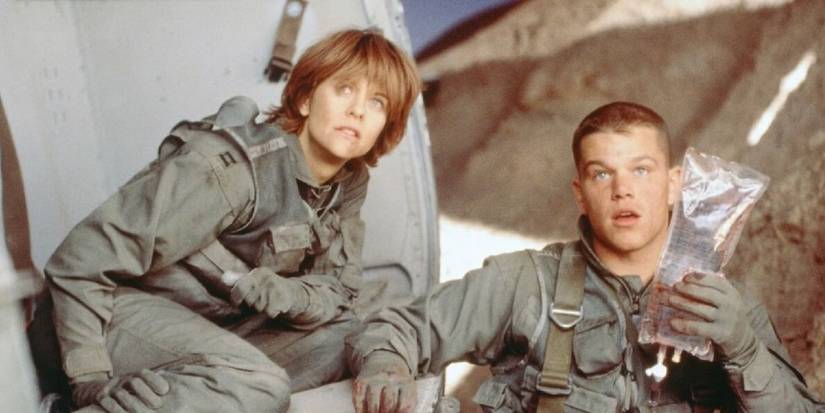 Matt Damon and Meg Ryan in matching uniforms look concerned at something off-screen in Courage Under Fire.