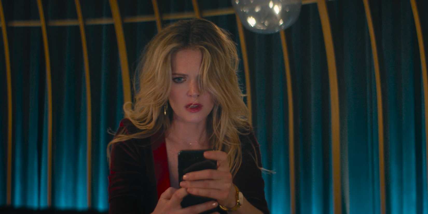Meghann Fahy as Violet Gates looking at her phone in Drop