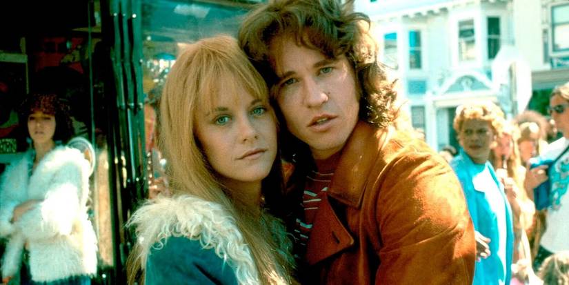 Meg Ryan as Pam and Val Kilmer as Jim pose cheek-to-cheek on a street and look at the camera in The Doors.