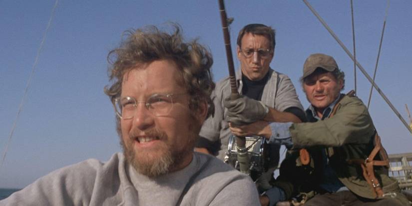 Richard Dreyfuss as Matt Hooper, with Roy Scheider and Robert Shaw as Martin Brody and Quint, holding a fishing rod behind him, in Jaws. 
