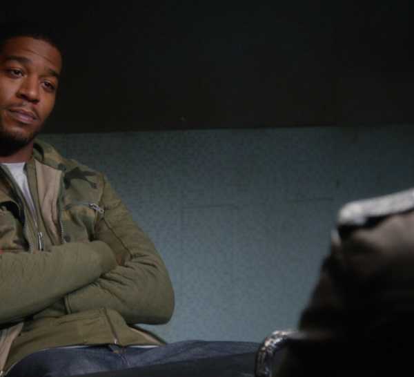 Dustin Whitman (played by Kid Cudi) sitting across from Jake Peralta (played by Andy Samberg), though you can only see some of Jake's back in "Brooklyn-Nine-Nine."