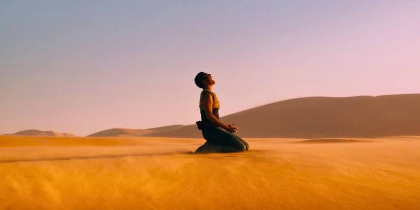 Furiosa, played by Charlize Theron, screams after falling to her knees on sand dunes in Mad Max: Fury Road.
